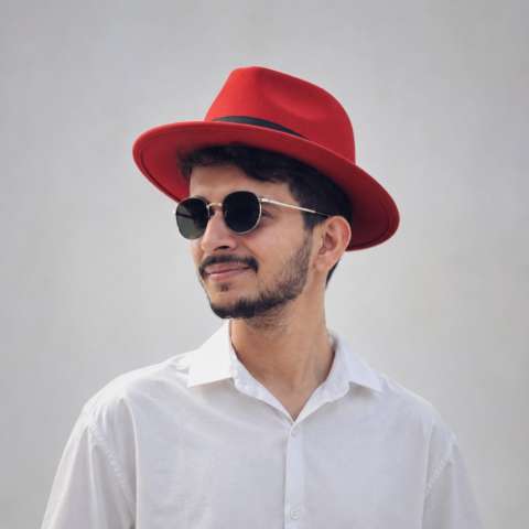 Author headshot: a man wearing a red fedora and sunglasses
